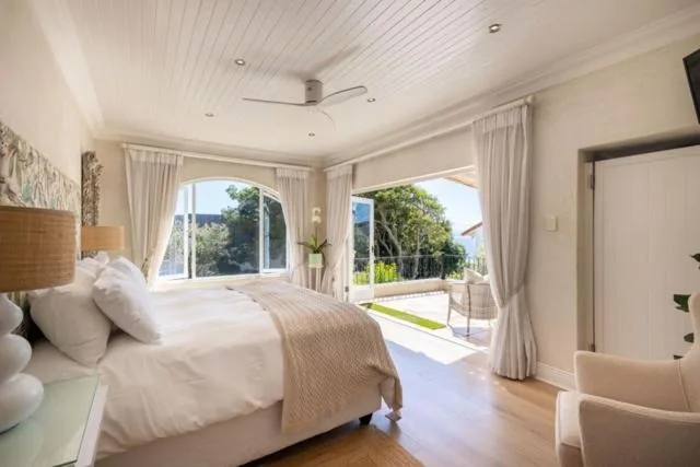 Bright bedroom with queen bed, large windows overlooking garden and mountains