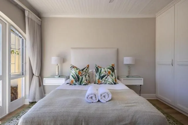 Bright bedroom with queen bed, tropical cushions, rolled towels, and garden view doors