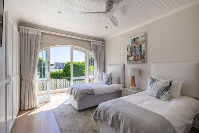 Twin bedroom with garden views through arched glass doors and balcony