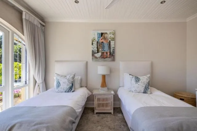 Twin beds with white linens and decorative pillows in bright bedroom