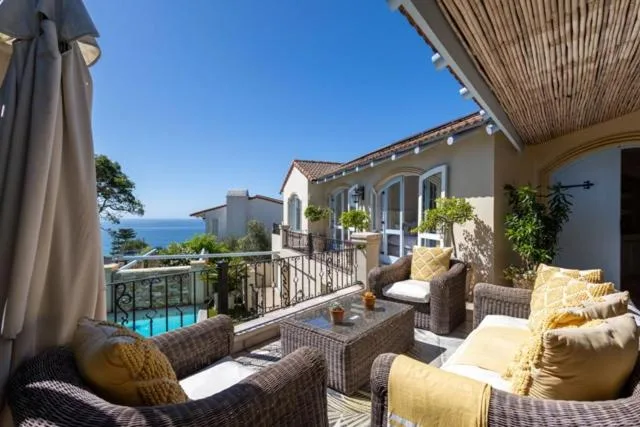 Covered deck with wicker furniture and sea view overlooking pool