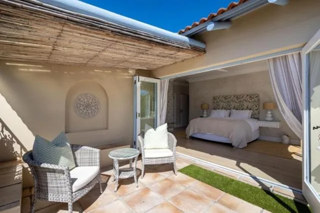 Covered patio with seating overlooking bedroom with terracotta tiles
