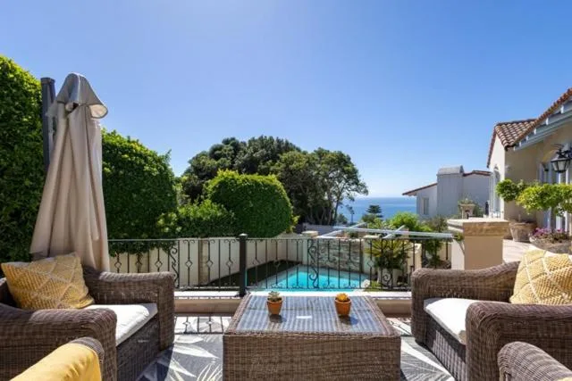 Outdoor seating area with woven chairs overlooking swimming pool and ocean view