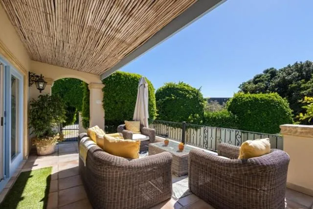 Outdoor deck with wicker seating, cushions, and lush greenery views