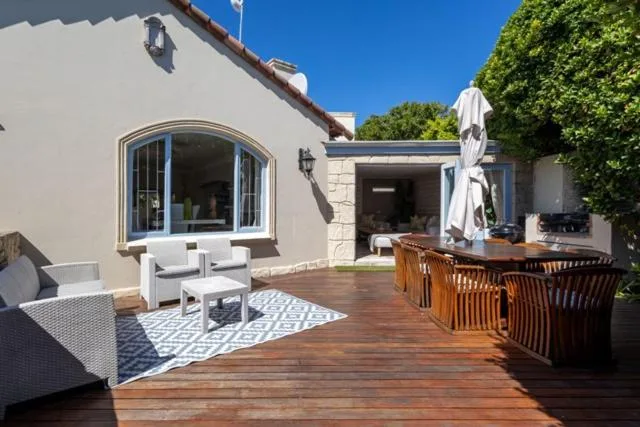 Wooden deck with white seating and umbrella overlooking property
