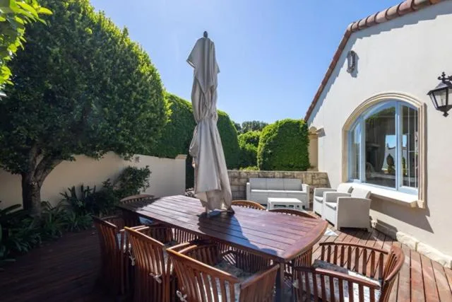 Wooden deck with dining table, umbrella, and garden seating area