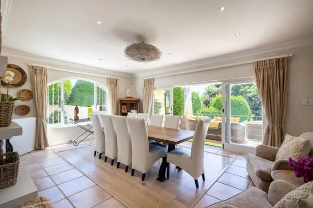 Spacious dining room with large table and cream upholstered chairs overlooking gardens
