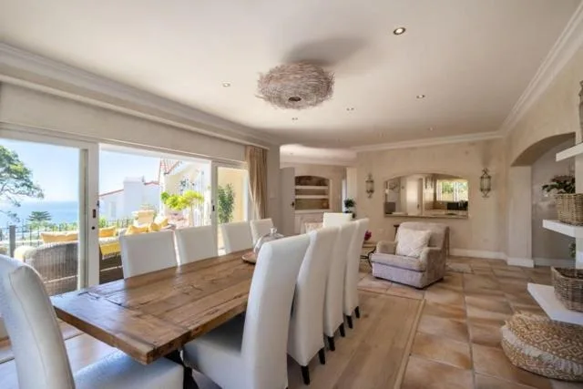 Open-plan dining area with wooden table and upholstered chairs, ocean view