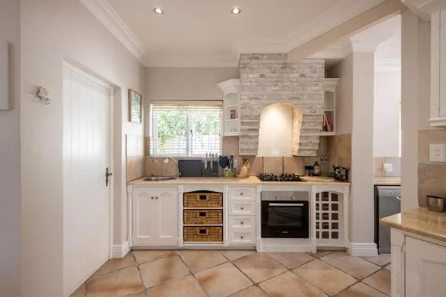 Modern kitchen with white cabinetry, gas stove, and brick accent wall