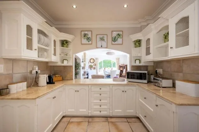 Bright white kitchen with cream countertops and open plan to lounge area