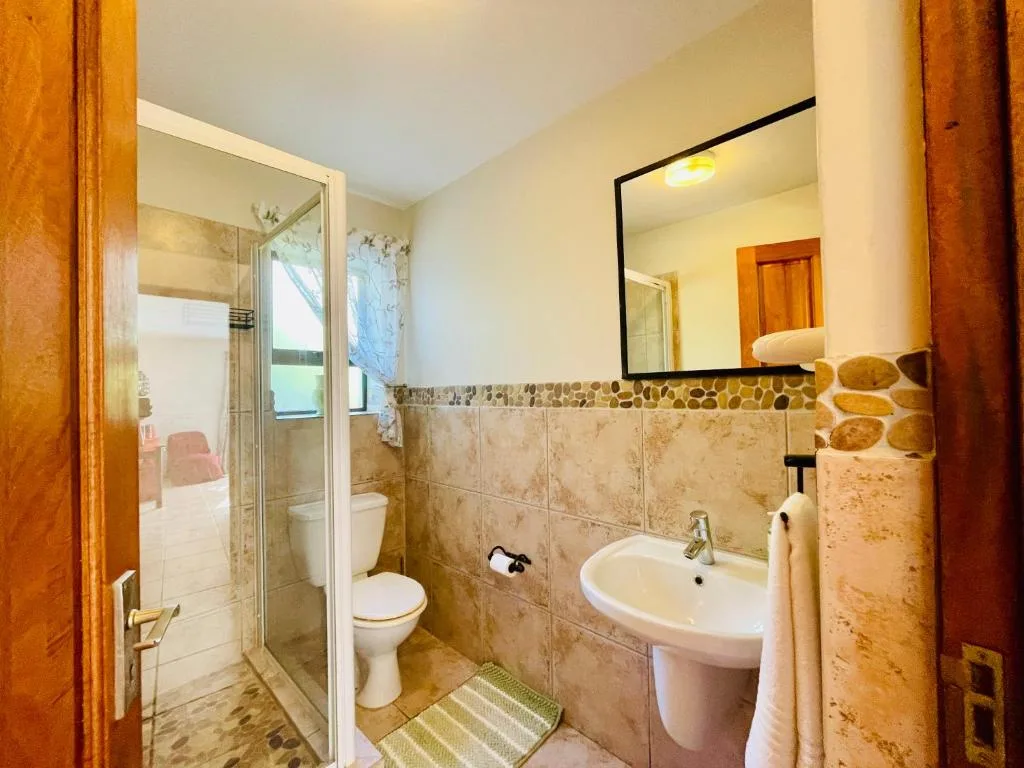 Bathroom with shower enclosure, vanity sink, and toilet fixtures