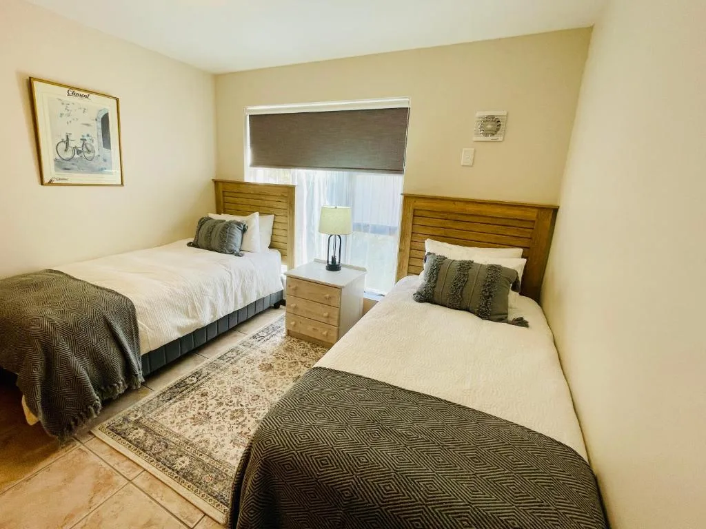 Bright bedroom with two single beds, wooden headboards, and patterned throws