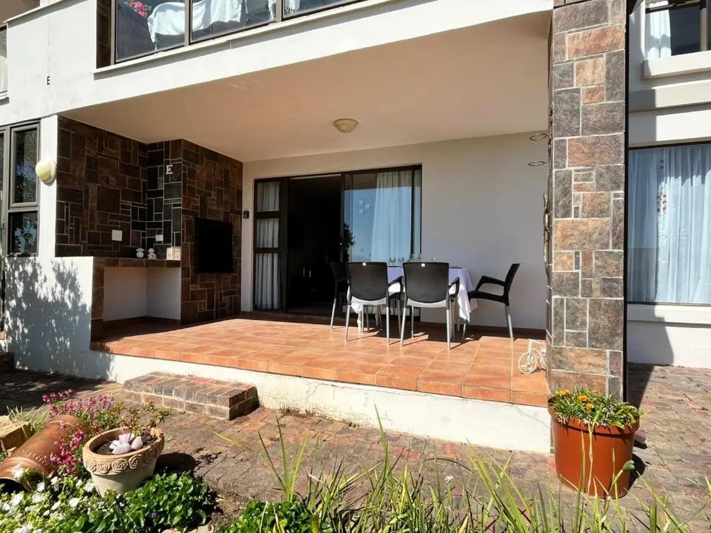 Covered patio with terracotta tiles, dining table, and stone fireplace