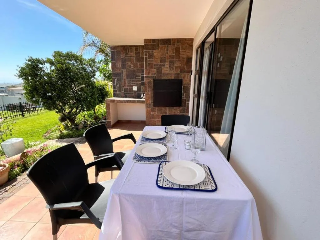 Outdoor patio with set dining table overlooking manicured garden lawn
