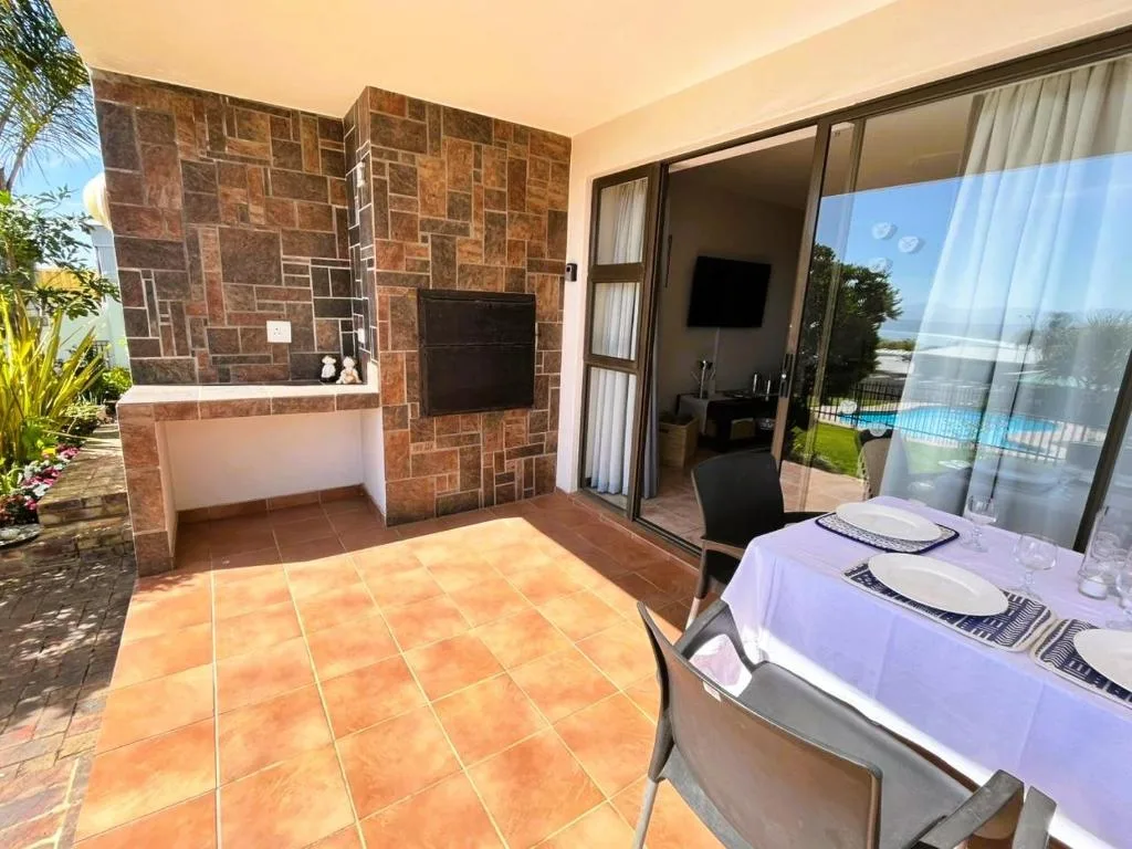 Outdoor patio area with terracotta tiles, dining setup, and pool views