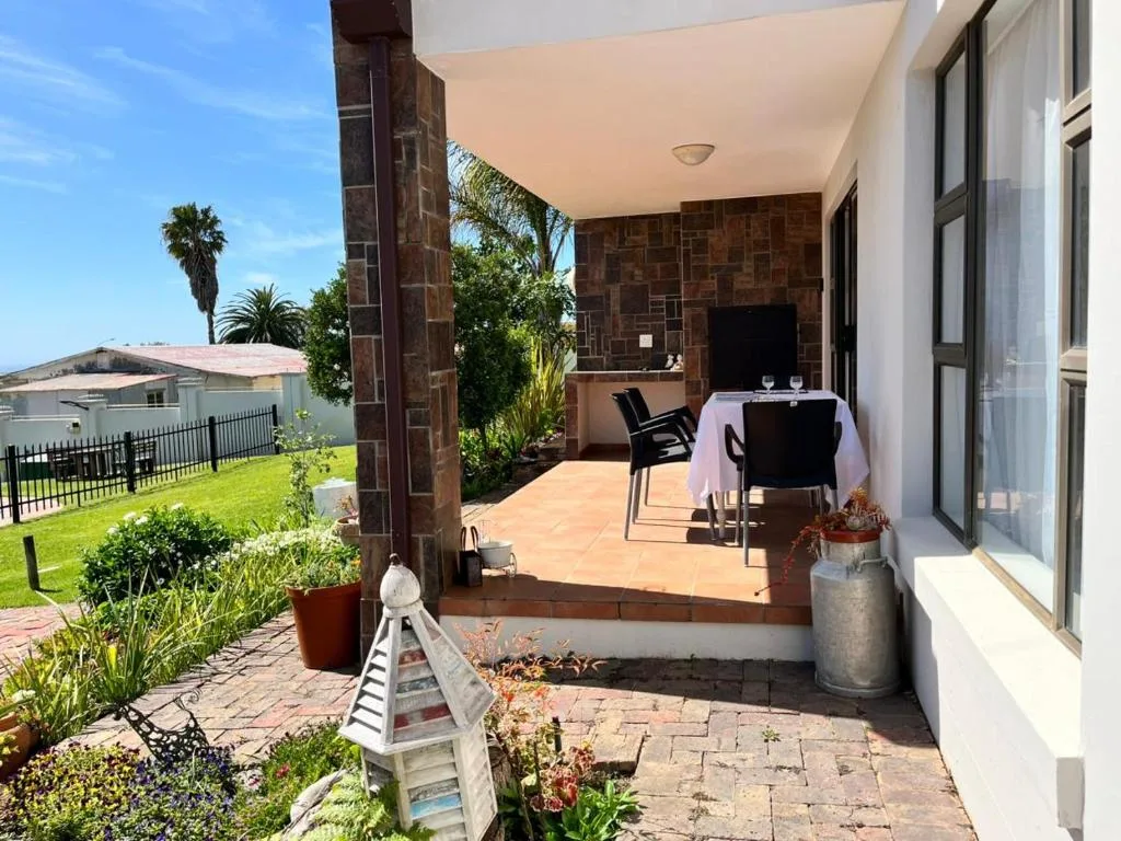 Covered patio with dining table, chairs, and garden views