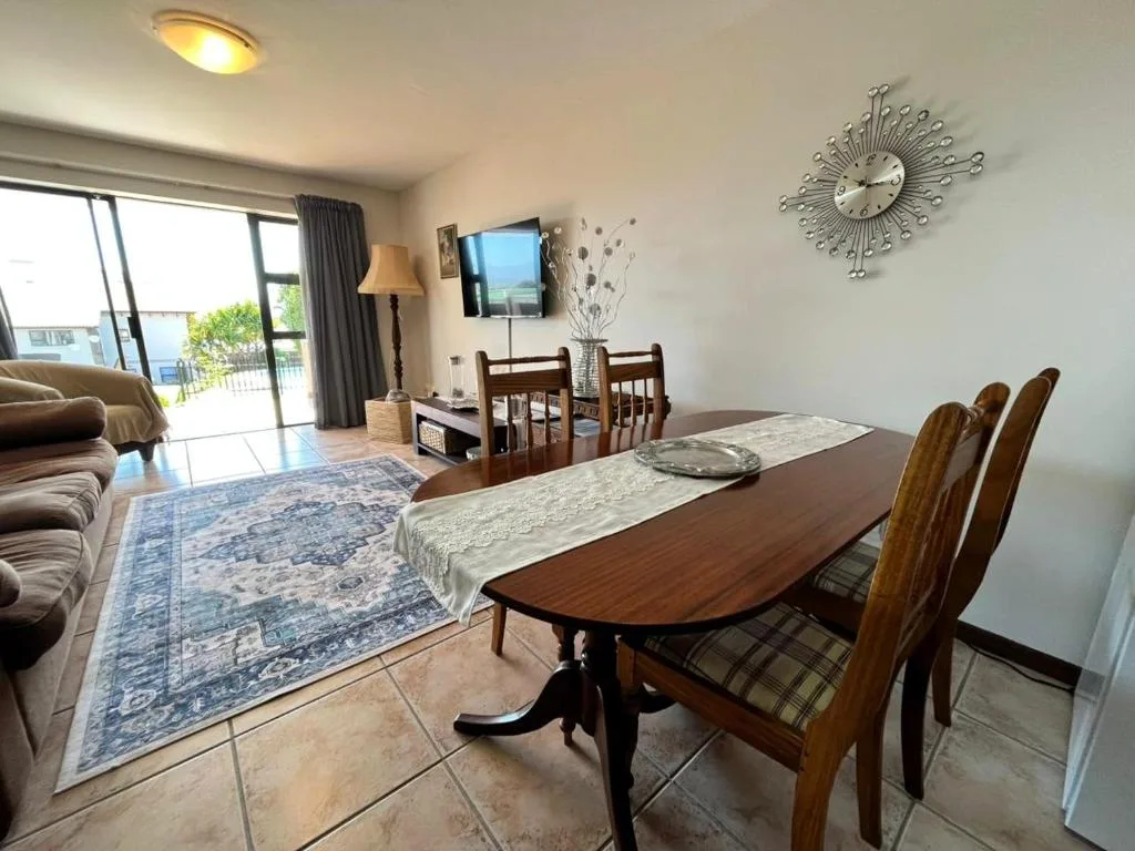 Wooden dining table with chairs in open-plan apartment with lounge area visible