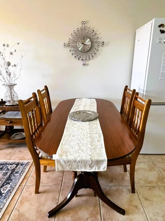 Wooden dining table with chairs, decorative clock, and table runner