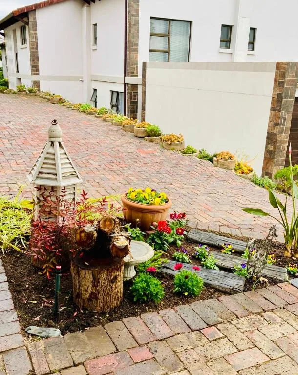 Brick driveway with decorative garden, flowering plants, and property entrance