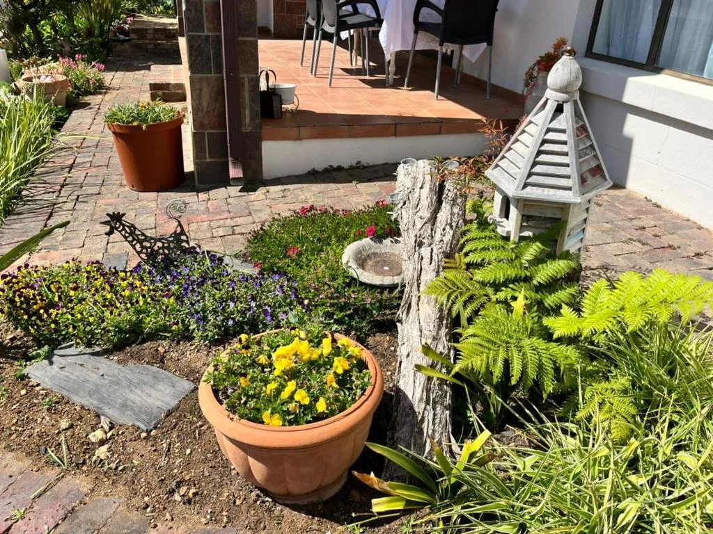 Sunny garden entrance with colorful flower pots and brick paving pathway