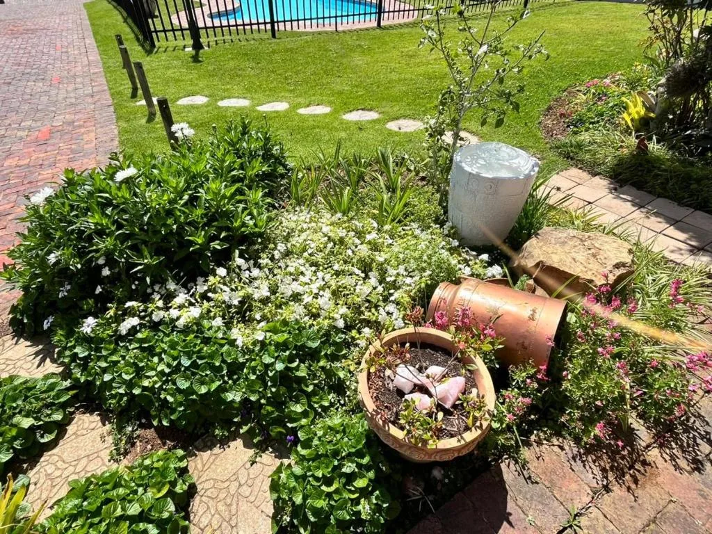 Lush garden with white flowering plants, decorative pots, and manicured lawn