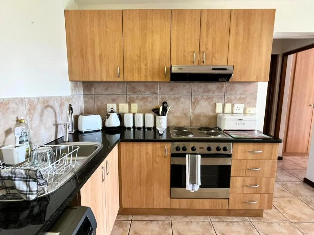 Modern kitchen with wooden cabinets, black countertops, and stainless steel appliances