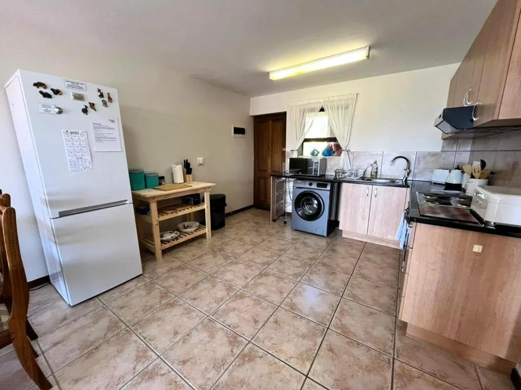 Spacious kitchen with white fridge, stove, washing machine, and wooden cabinetry