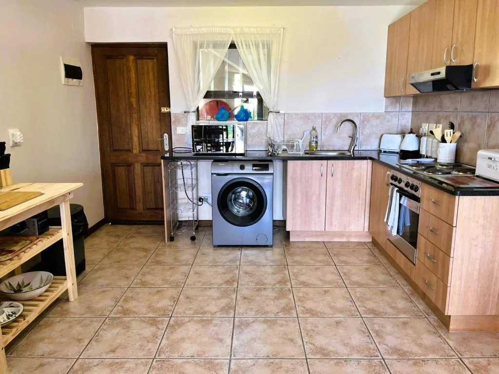 Spacious kitchen with wooden cabinetry, stove, washing machine, and tiled flooring
