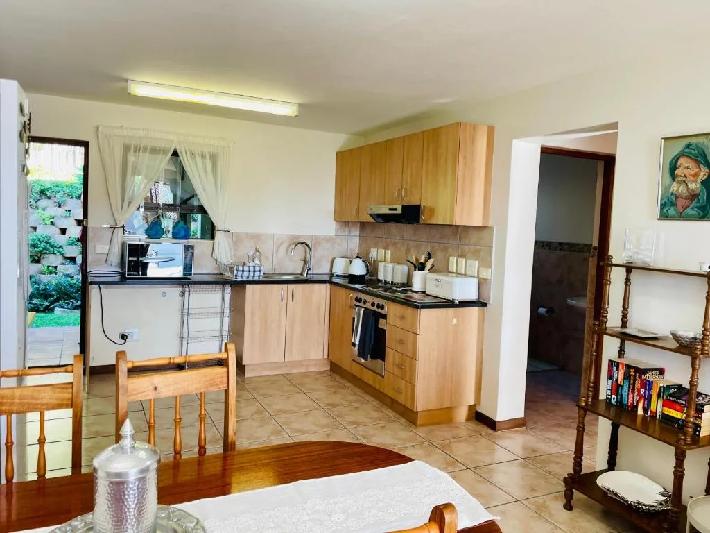 Open-plan kitchen with wooden cabinetry, black countertops, and gas stove