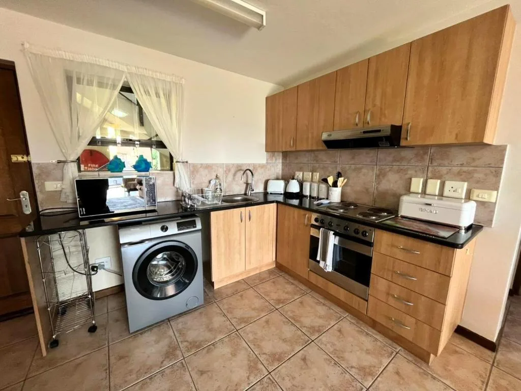 Modern kitchen with wooden cabinetry, black countertops, and stainless steel appliances