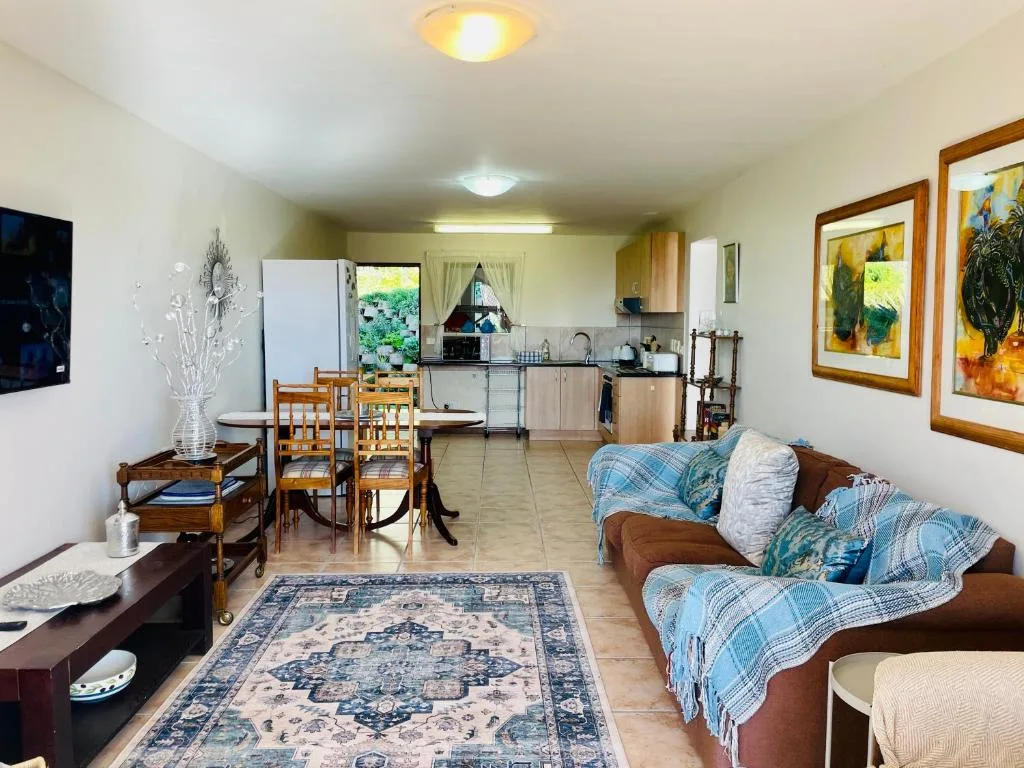 Open-plan lounge with brown sofa, dining table, and kitchen area visible