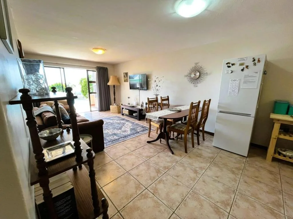 Open-plan lounge and dining area with sofa, TV, and dining table