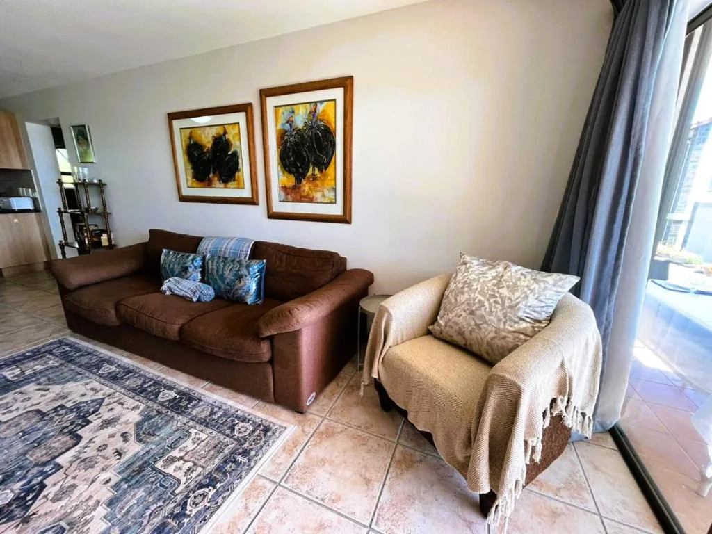 Spacious lounge with brown sofa, cream armchair, and framed artwork on walls