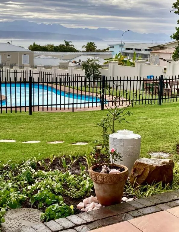Swimming pool with black safety fencing overlooking garden and mountains