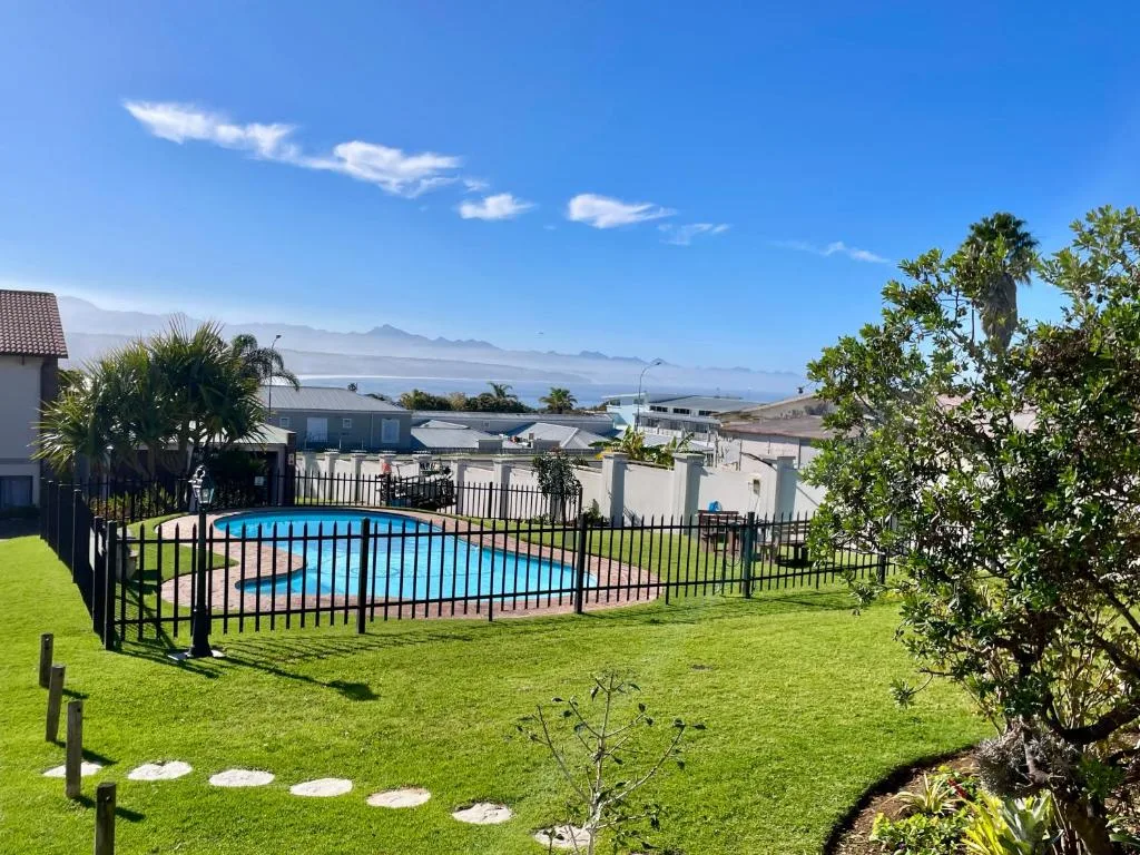 Mountain vista across lush green garden with fenced swimming pool below