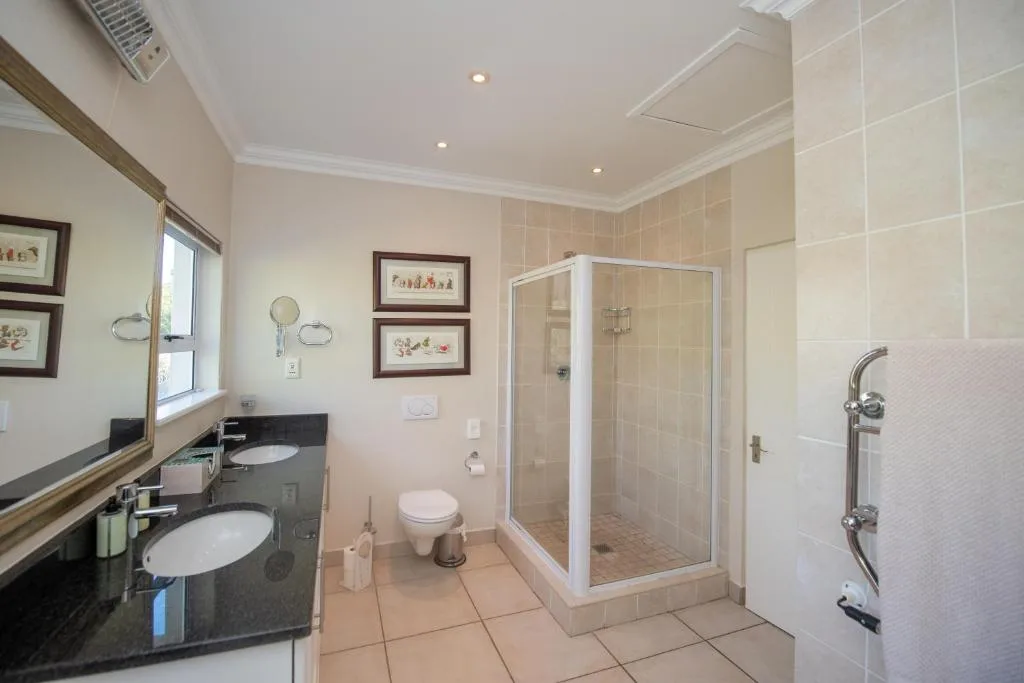 Spacious bathroom with double vanity, glass shower enclosure, and window