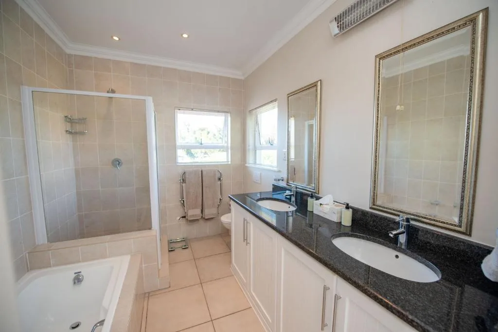 Spacious bathroom with dual vanity, shower enclosure, and natural light