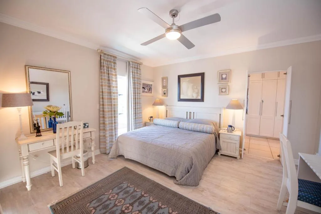 Spacious bedroom with queen bed, vanity desk, and coastal decor