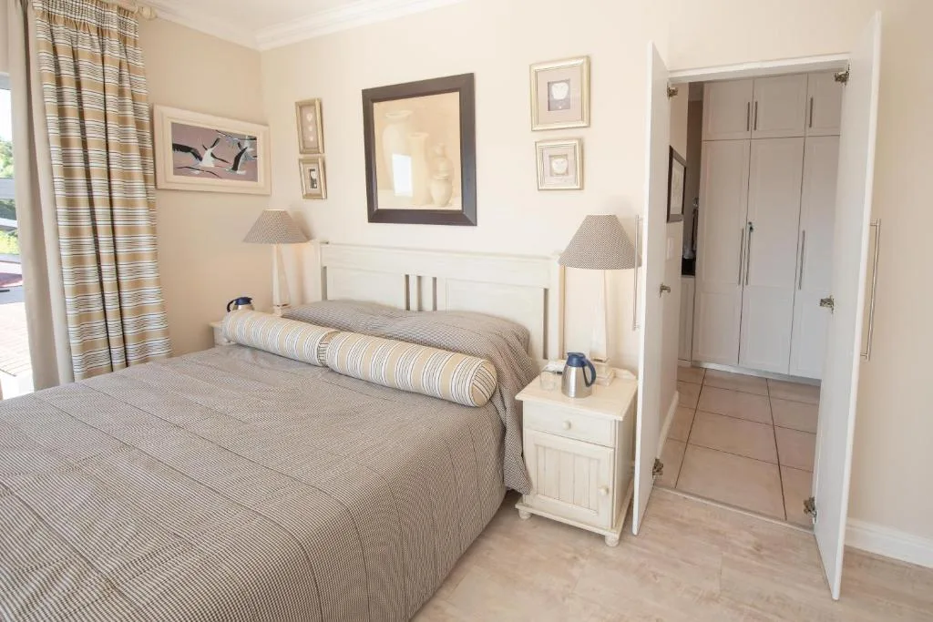 Spacious bedroom with double bed, white furniture, and built-in wardrobes