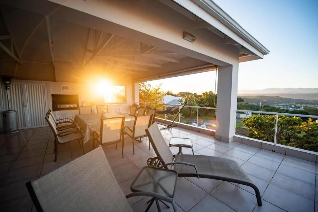 Covered patio with dining chairs overlooking valley and mountains at sunset