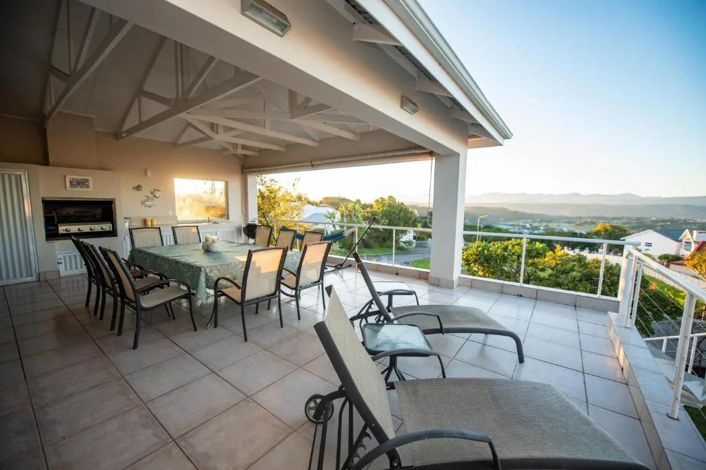 Covered patio with dining table and lounge chairs overlooking valley
