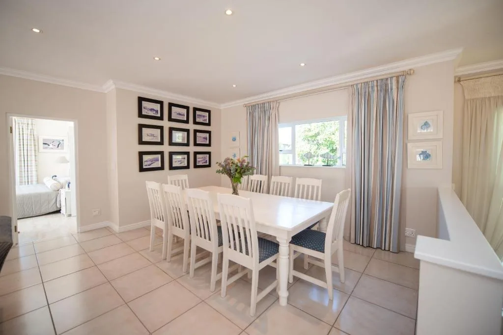 Elegant dining room with white table, eight chairs, and framed artwork