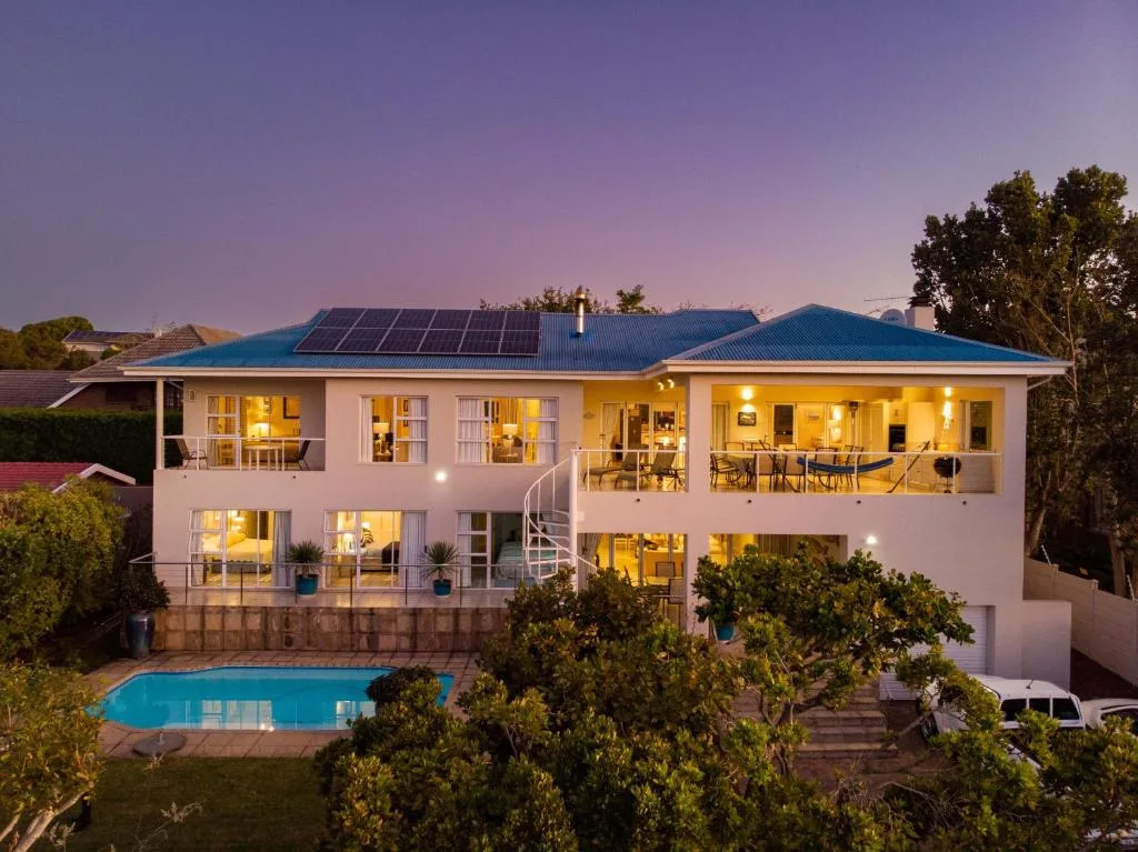 Modern white two-story house with blue roof and swimming pool at dusk