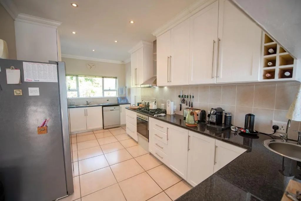 Bright modern kitchen with white cabinetry, black countertops, and stainless steel appliances