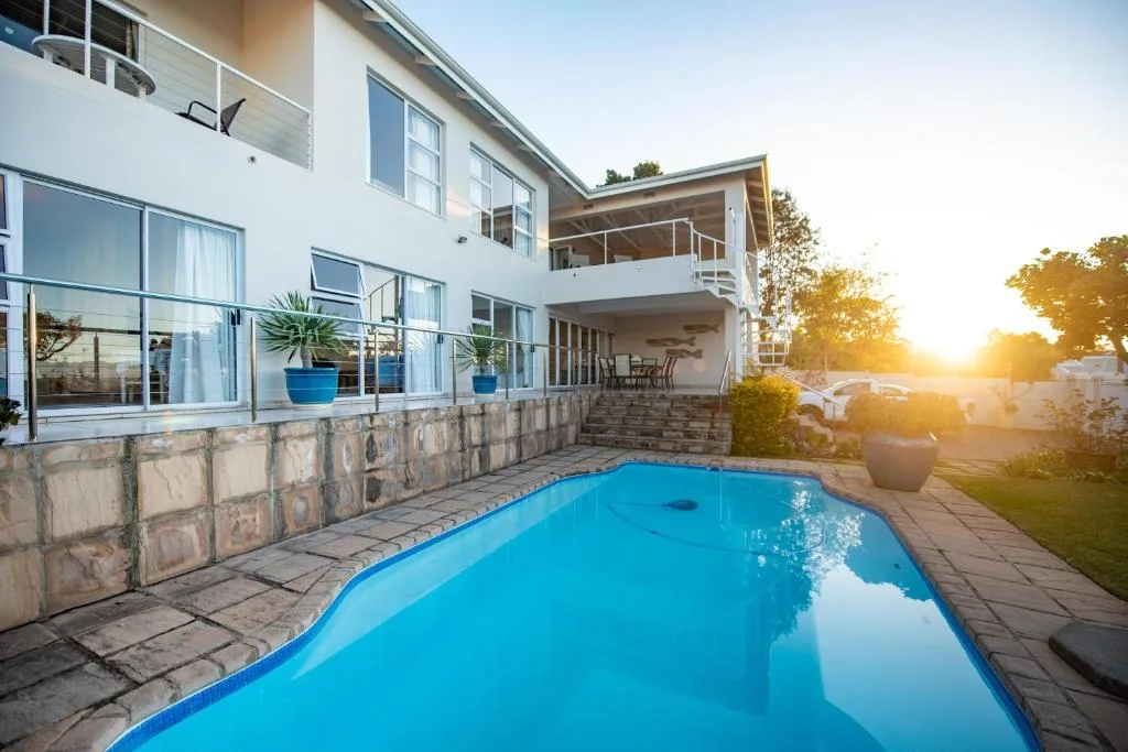 Bright blue swimming pool with modern white house and sunset view