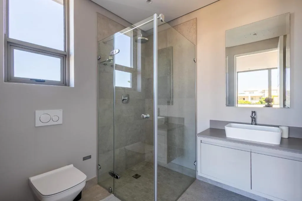 Modern bathroom with glass shower enclosure, white toilet, and vessel sink vanity