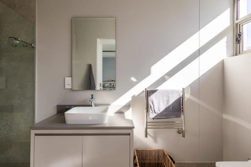 Modern bathroom with vessel sink, mirror, towel rail, and natural light