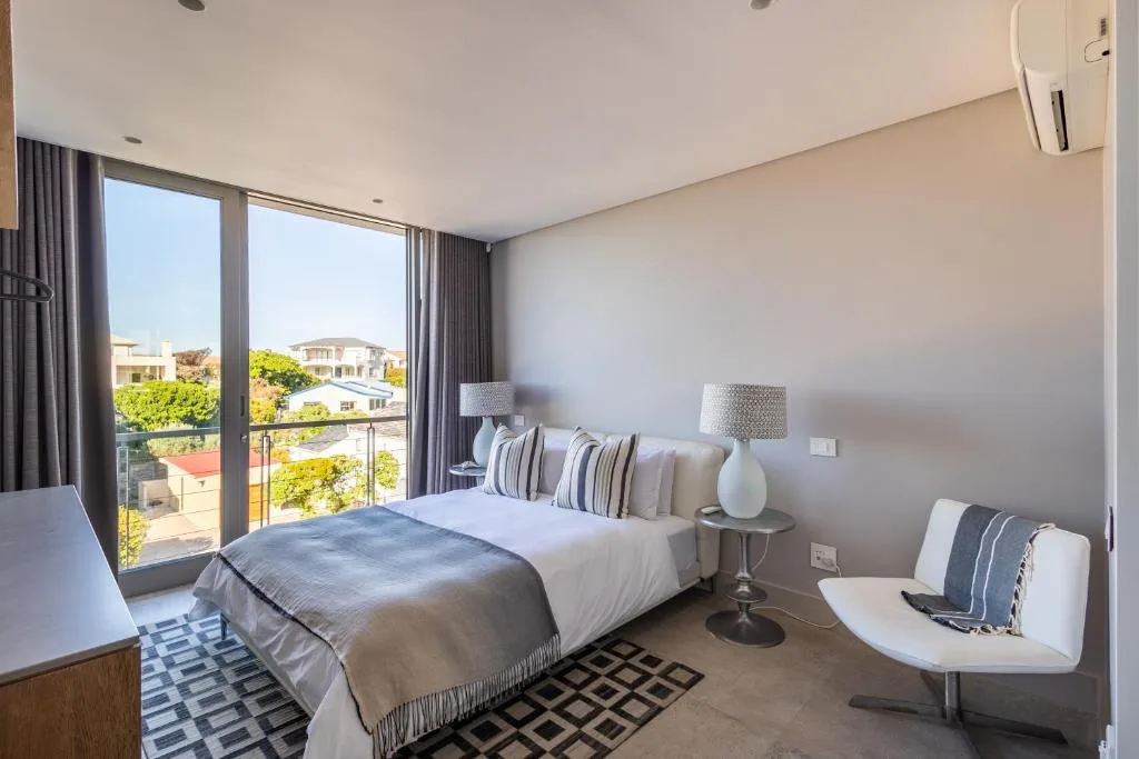 Spacious bedroom with queen bed, large windows overlooking neighboring properties