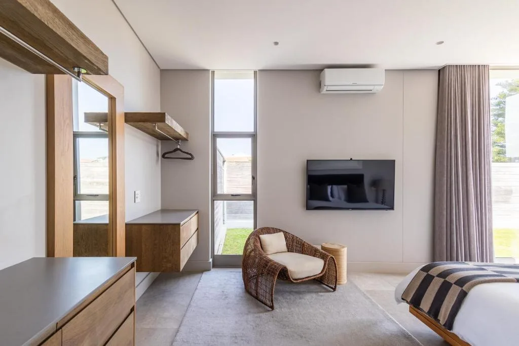 Modern bedroom with wicker chair, TV, and built-in wardrobe with garden views