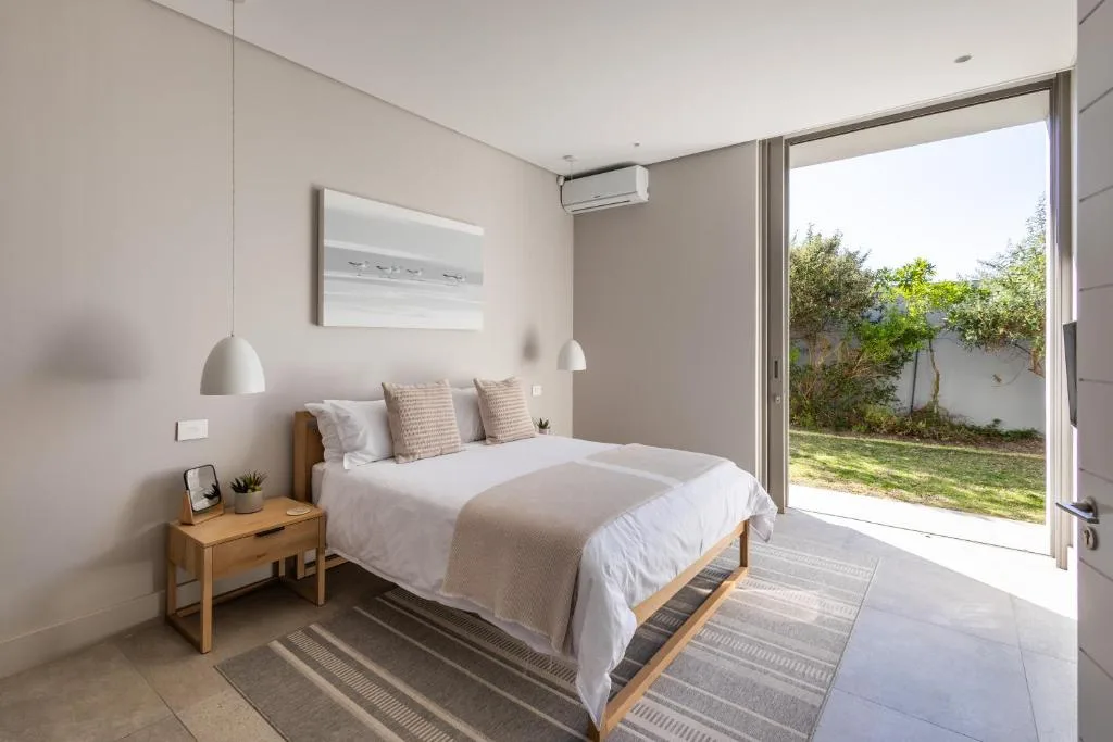 Modern bedroom with queen bed, pendant lights, and garden view through sliding doors